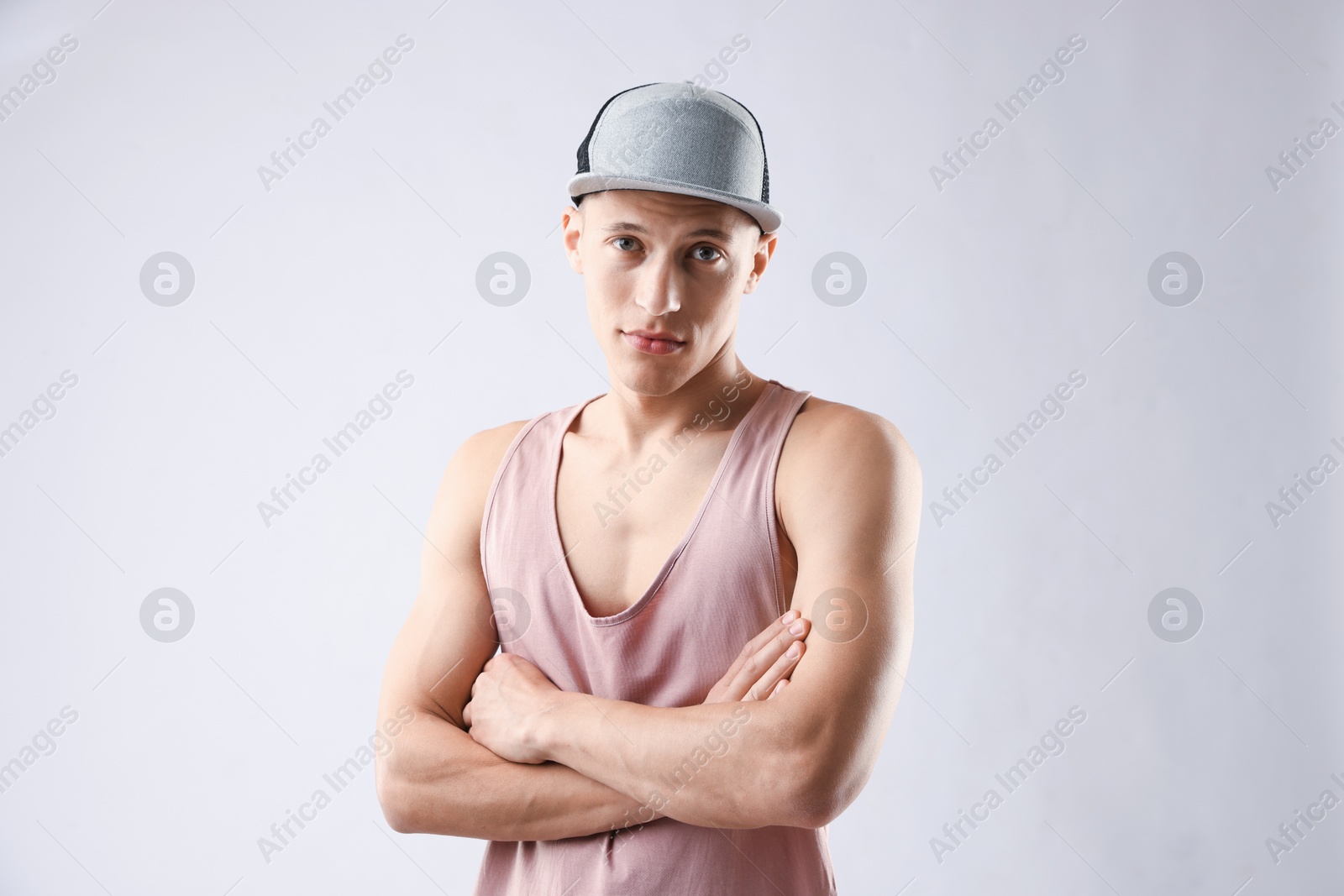 Young man in stylish baseball hat on light grey background Photo of Young man in stylish baseball hat on light grey background