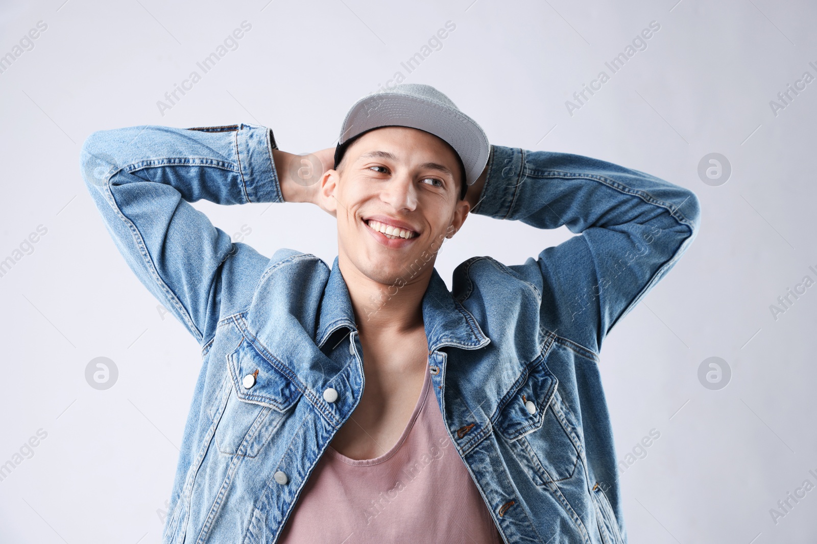 Young man in stylish baseball hat on light grey background Photo of Young man in stylish baseball hat on light grey background