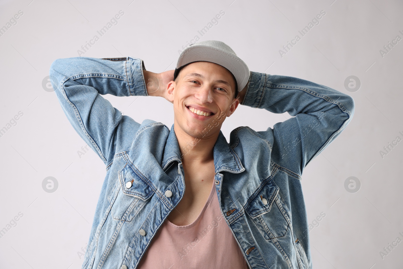 Young man in stylish baseball hat on light grey background Photo of Young man in stylish baseball hat on light grey background