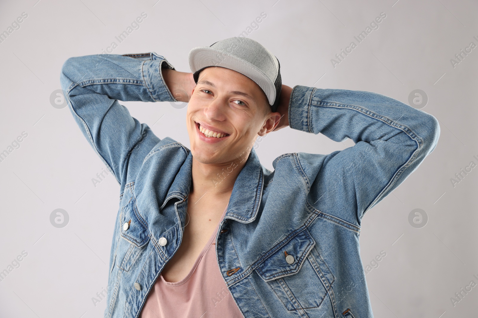 Young man in stylish baseball hat on light grey background Photo of Young man in stylish baseball hat on light grey background