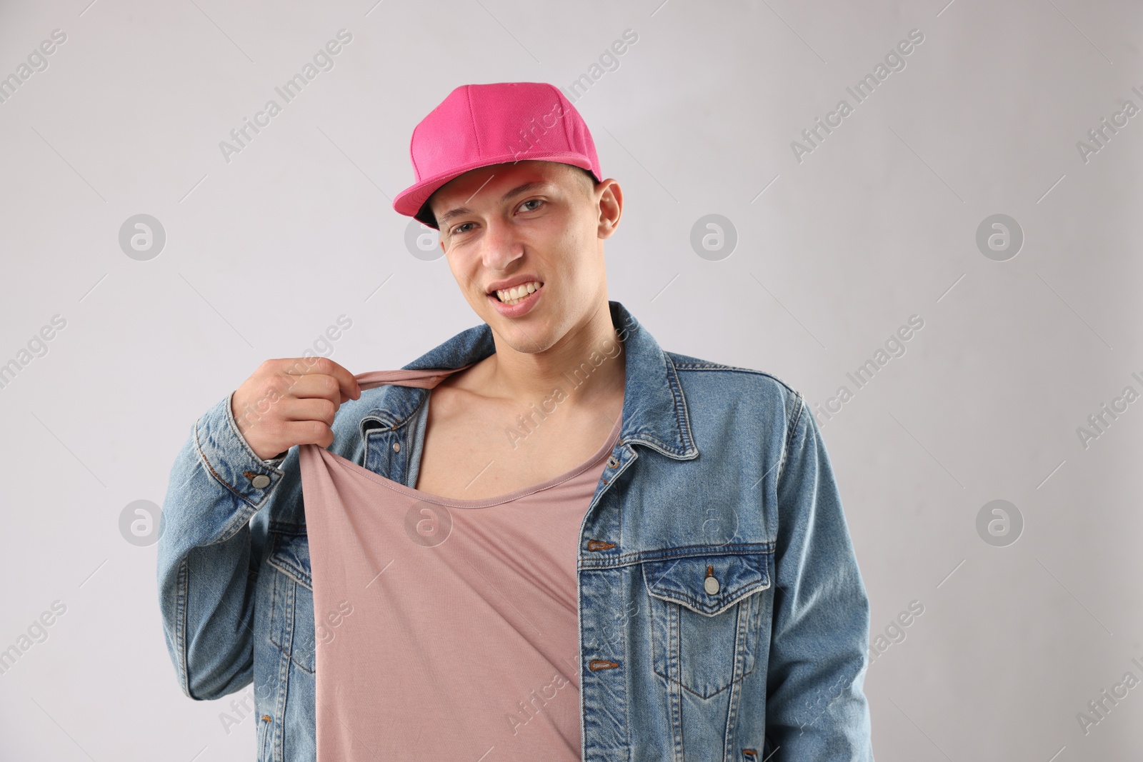 Young man in stylish baseball hat on light grey background Photo of Young man in stylish baseball hat on light grey background