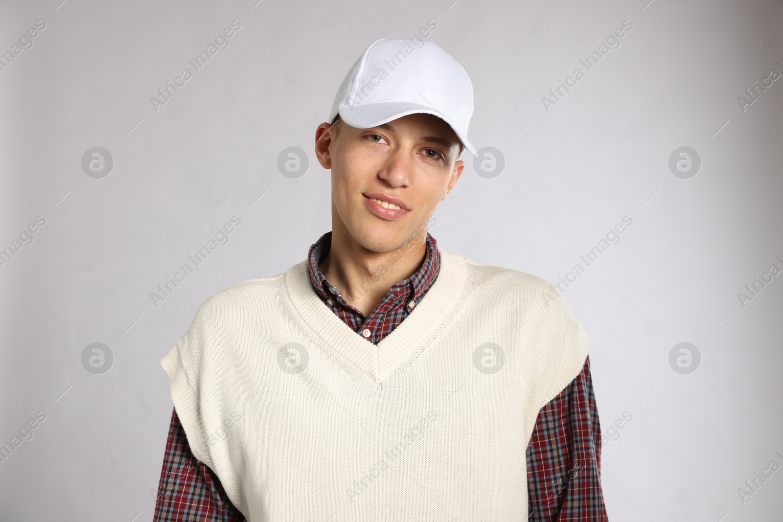 Young man in stylish baseball hat on light grey background Photo of Young man in stylish baseball hat on light grey background