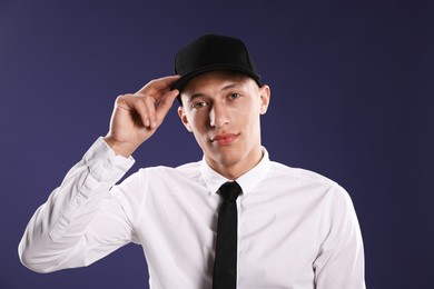 Photo of Young man in stylish baseball hat on dark blue background