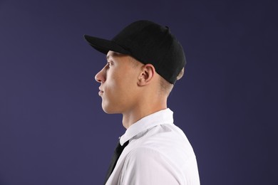 Photo of Young man in stylish baseball hat on dark blue background