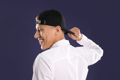 Photo of Young man in stylish baseball hat on dark blue background