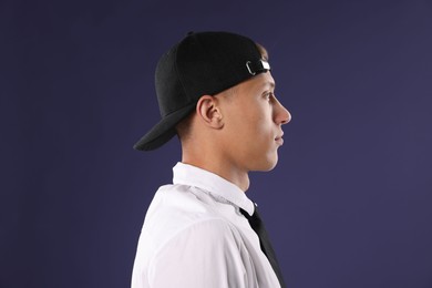 Photo of Young man in stylish baseball hat on dark blue background
