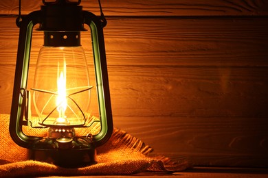 Photo of Vintage kerosene lamp on wooden table, closeup. Space for text