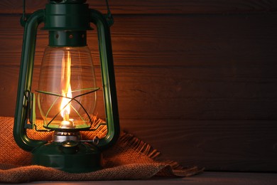 Photo of Vintage kerosene lamp on wooden table, closeup. Space for text