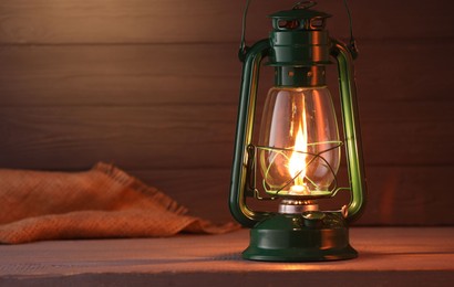 Photo of Vintage kerosene lamp on wooden table. Space for text