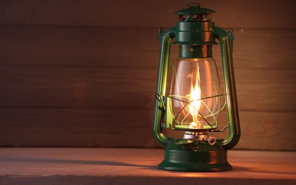 Photo of Vintage kerosene lamp on wooden table. Space for text