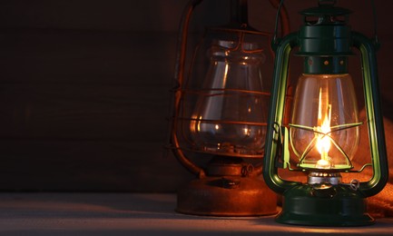 Photo of Vintage kerosene metal lamps on wooden table. Space for text
