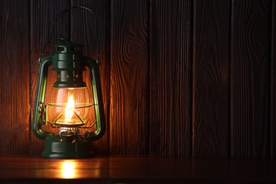 Photo of Vintage kerosene lamp on wooden table. Space for text