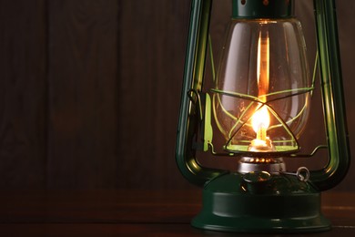 Photo of Vintage kerosene lamp on wooden table, closeup. Space for text