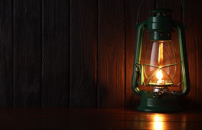 Photo of Vintage kerosene lamp on wooden table. Space for text