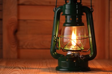 Photo of Vintage kerosene lamp on wooden table, closeup. Space for text