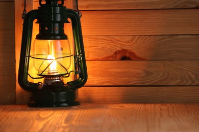 Photo of Vintage kerosene lamp on wooden table. Space for text