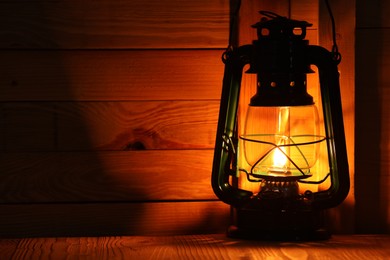 Photo of Vintage kerosene lamp on wooden table. Space for text