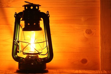 Photo of Vintage kerosene lamp on wooden table, closeup. Space for text