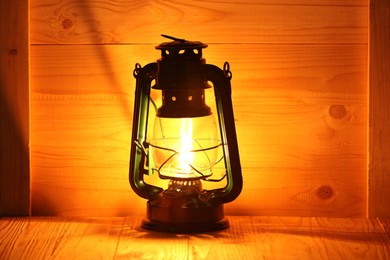 Photo of Burning vintage kerosene lamp on wooden table