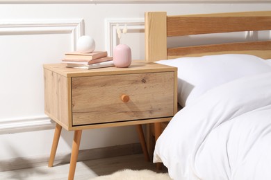 Photo of Bedside table with books and decor near bed indoors