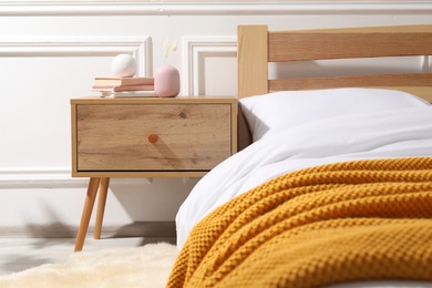 Photo of Bedside table with books and decor near bed indoors