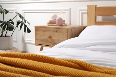 Photo of Bedside table with books and decor near bed indoors