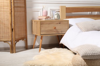 Photo of Bedside table with alarm clock, books and decor near bed indoors