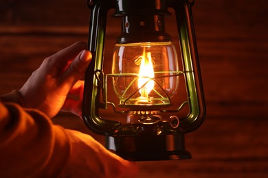 Photo of Man with vintage kerosene lamp on wooden background, closeup