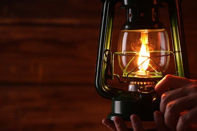 Photo of Man with vintage kerosene lamp on wooden background, closeup. Space for text