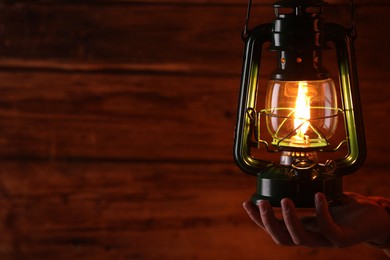 Photo of Man with vintage kerosene lamp on wooden background, closeup. Space for text