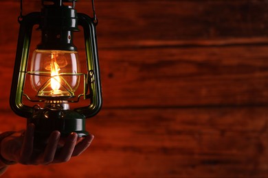 Photo of Man with vintage kerosene lamp on wooden background, closeup. Space for text