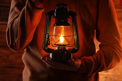 Photo of Man with vintage kerosene lamp on wooden background, closeup