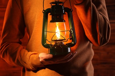 Photo of Man with vintage kerosene lamp on wooden background, closeup