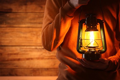 Photo of Man with vintage kerosene lamp on wooden background, closeup. Space for text