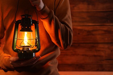 Photo of Man with vintage kerosene lamp on wooden background, closeup. Space for text