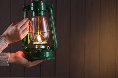 Photo of Man with vintage kerosene lamp on wooden background, closeup. Space for text