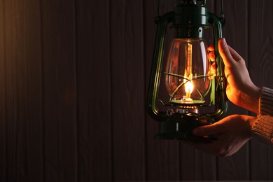 Photo of Man with vintage kerosene lamp on wooden background, closeup. Space for text