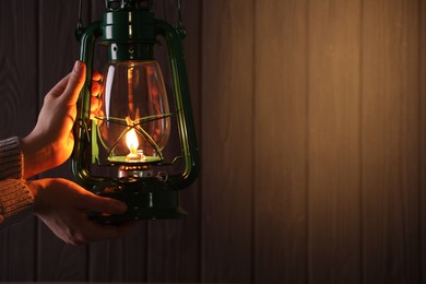Photo of Man with vintage kerosene lamp on wooden background, closeup. Space for text