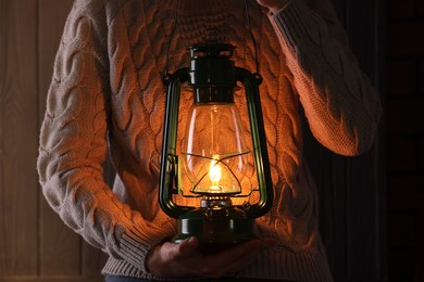 Photo of Man with vintage kerosene lamp on wooden background, closeup