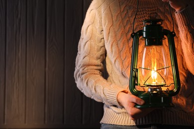 Photo of Man with vintage kerosene lamp on wooden background, closeup. Space for text