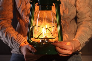 Photo of Man with vintage kerosene lamp on wooden background, closeup