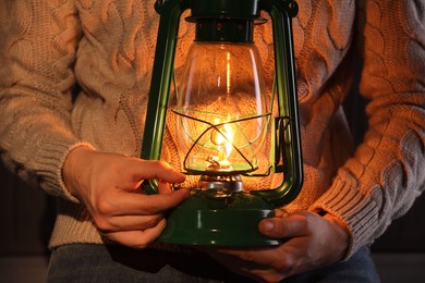 Photo of Man with vintage kerosene lamp on wooden background, closeup
