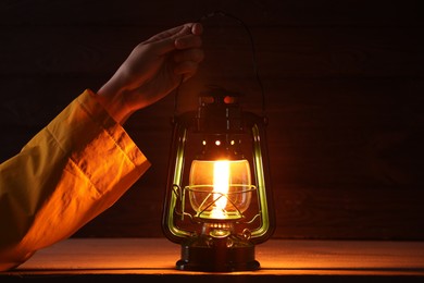 Photo of Man with vintage kerosene lamp on wooden background, closeup