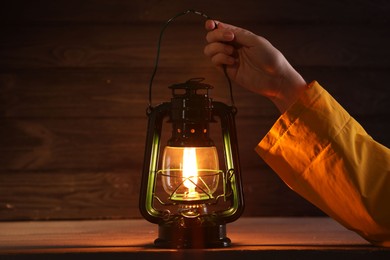 Photo of Man with vintage kerosene lamp on wooden background, closeup