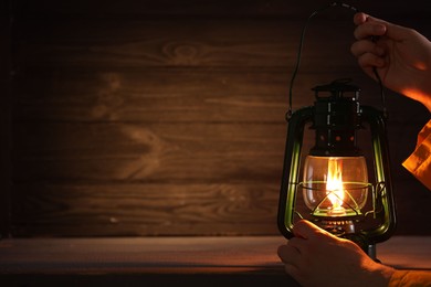 Photo of Man with vintage kerosene lamp on wooden background, closeup. Space for text