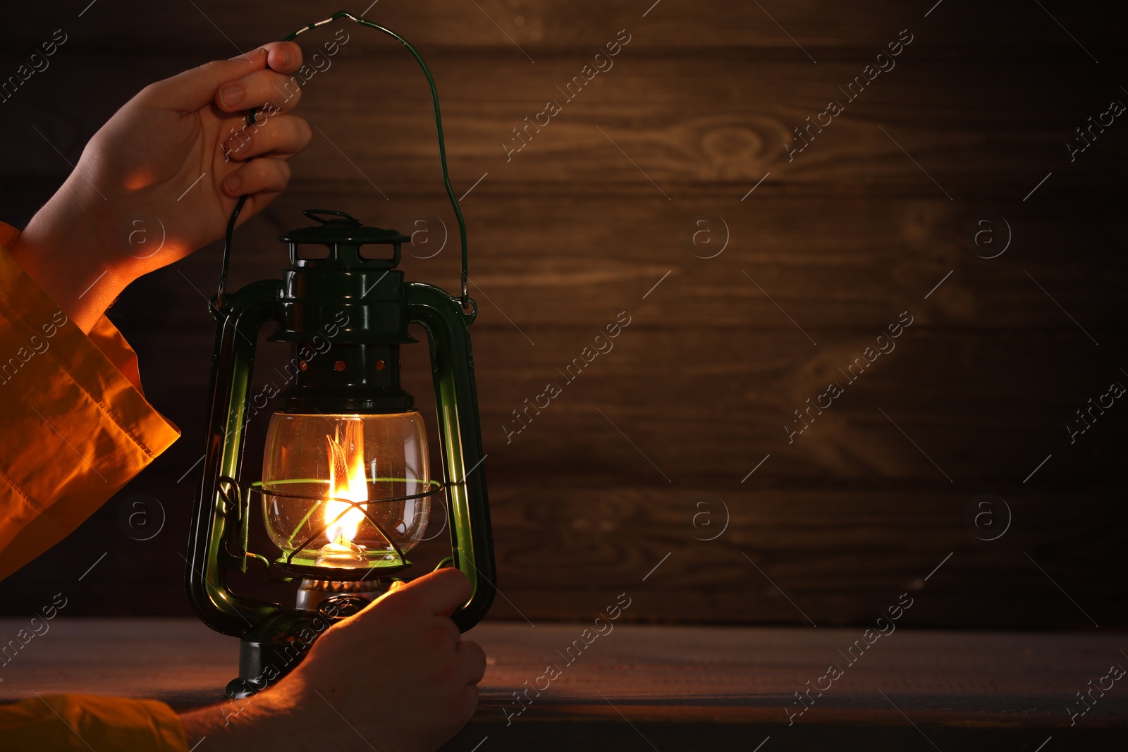 Man with vintage kerosene lamp on wooden background, closeup. Space for text Photo of Man with vintage kerosene lamp on wooden background, closeup. Space for text