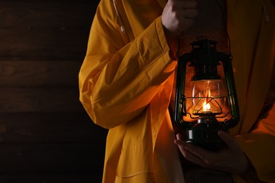 Photo of Man with vintage kerosene lamp on wooden background, closeup