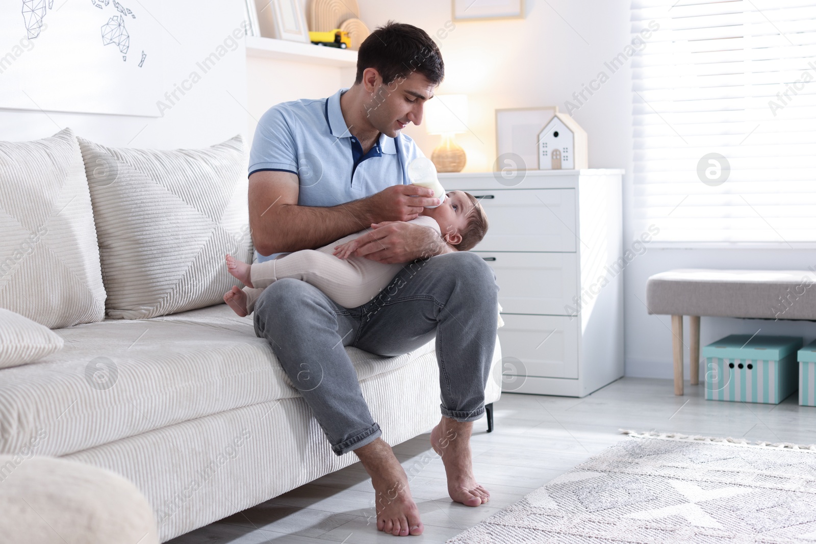 Father feeding his little baby with bottle on sofa at home Photo of Father feeding his little baby with bottle on sofa at home