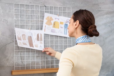 Photo of Professional stylist with pictures of outfits indoors