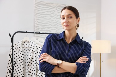 Photo of Portrait of professional stylist near clothing rack indoors